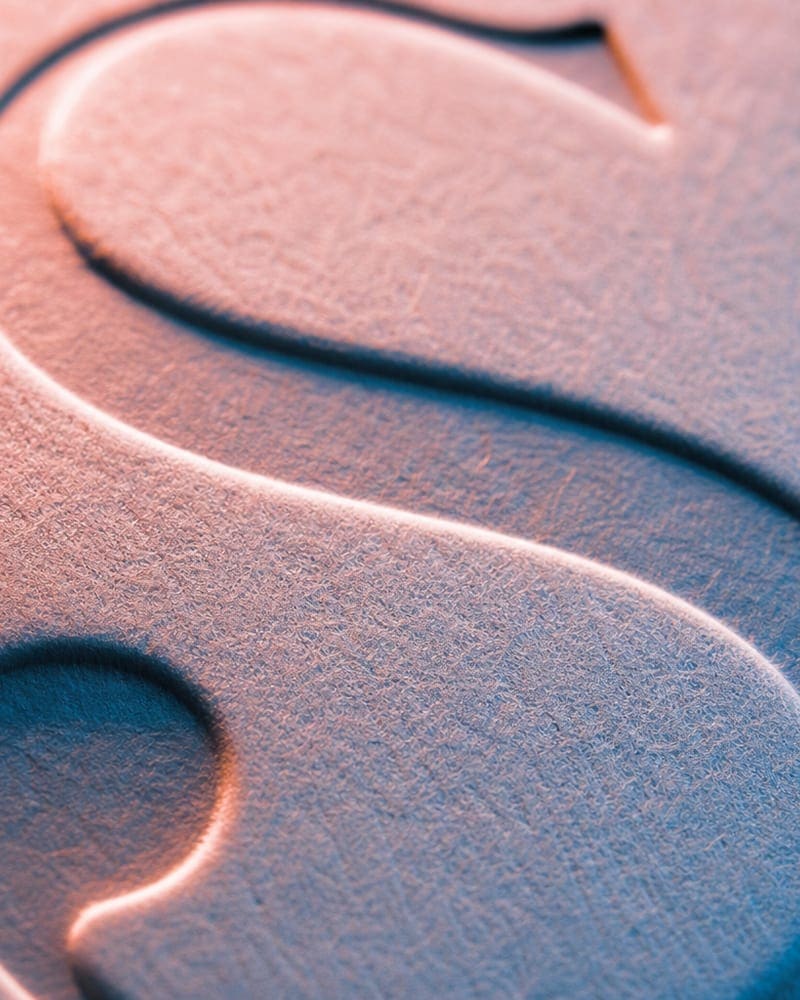 Close-up of copper foil stamp impression on cream paper showing debossed letterforms.